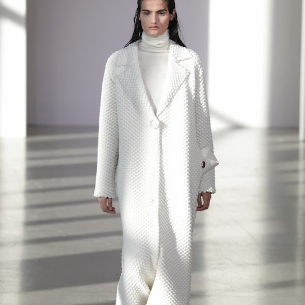 a model wearing a white duster coat on the Bevza runway