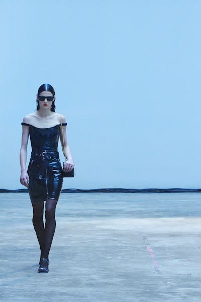 a model a black leather off-the-shoulder dress on the Khaite runway