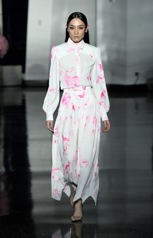 a model wearing a white and pink printed blouse and skirt on the Christian Cowan runway