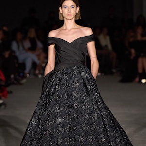 Model in black full-skirted A-line off-the-shoulder dress on Christian Cyrano runway