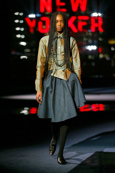 a model wearing a marigold full knee-length skirt on the Tory Burch runway