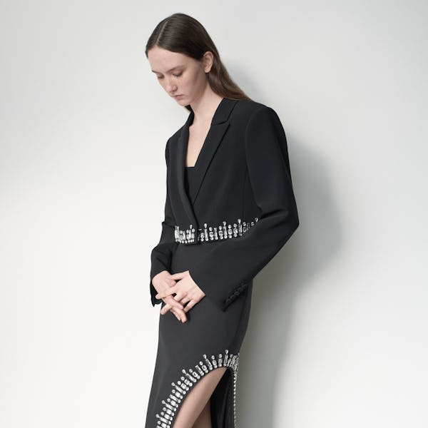 a model wearing a rhinestone-adorned black blazer and skirt by Cinq à Sept
