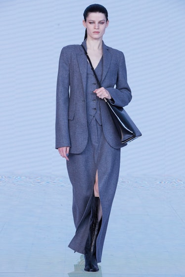 Model on the NY Fashion Week Fall 2022 runway in a Peter Do gray suit and a black bag