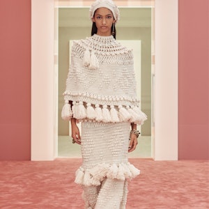 A model in an ivory knitted poncho and skirt with tassels on the Zimmermann runway