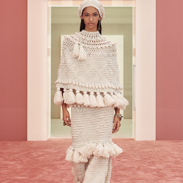 a model wearing an ivory knit poncho and skirt with tassels on the Zimmermann runway