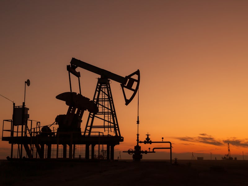 Oil pump extracting fossil fuels at sunset