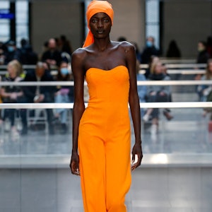 A model in a marigold jumpsuit on the runway for Victor Gremaud