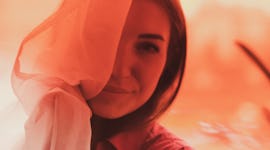 Young women peeking out from behind a curtain on at 2:22 on 2/22/22, after she keeps seeing the same...