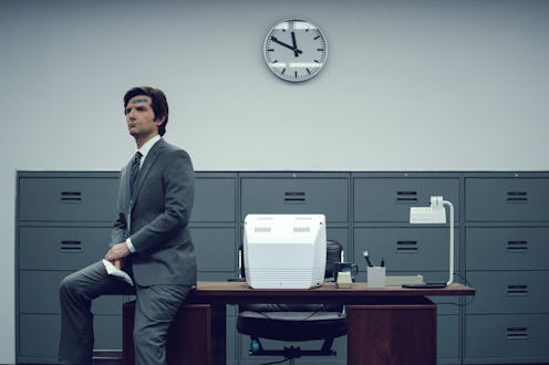 Adam Scott as Mark Scout in the Apple TV+ series “Severance,”  sitting on the edge of a desk in a ba...