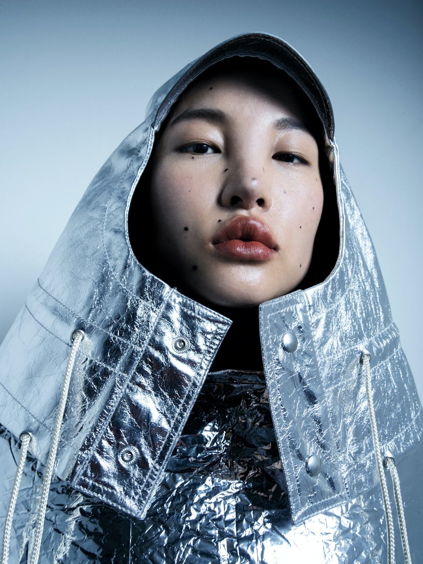 Portrait of a model with a silver hood and jacket, showing off her clear skin