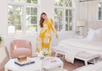 Miranda Kerr standing in her bed room while wearing a yellow and white floral dress
