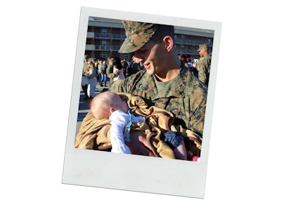 Man in military fatigues holds his new baby.