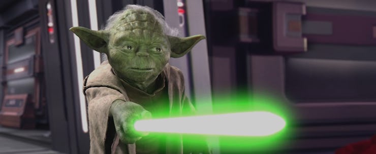 Yoda pointing a light saber toward something in front of him