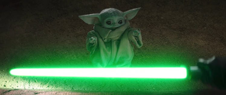 Grogu looking at Yoda's lightsaber on the floor 