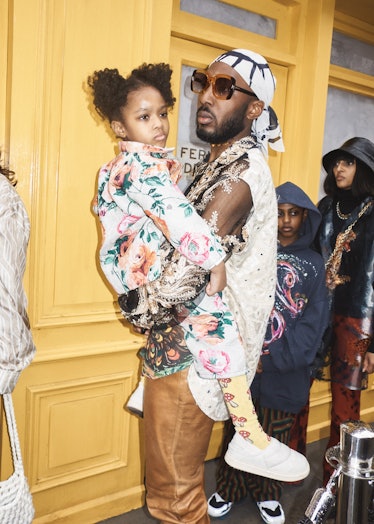 A person carrying a child at London Fashion Week