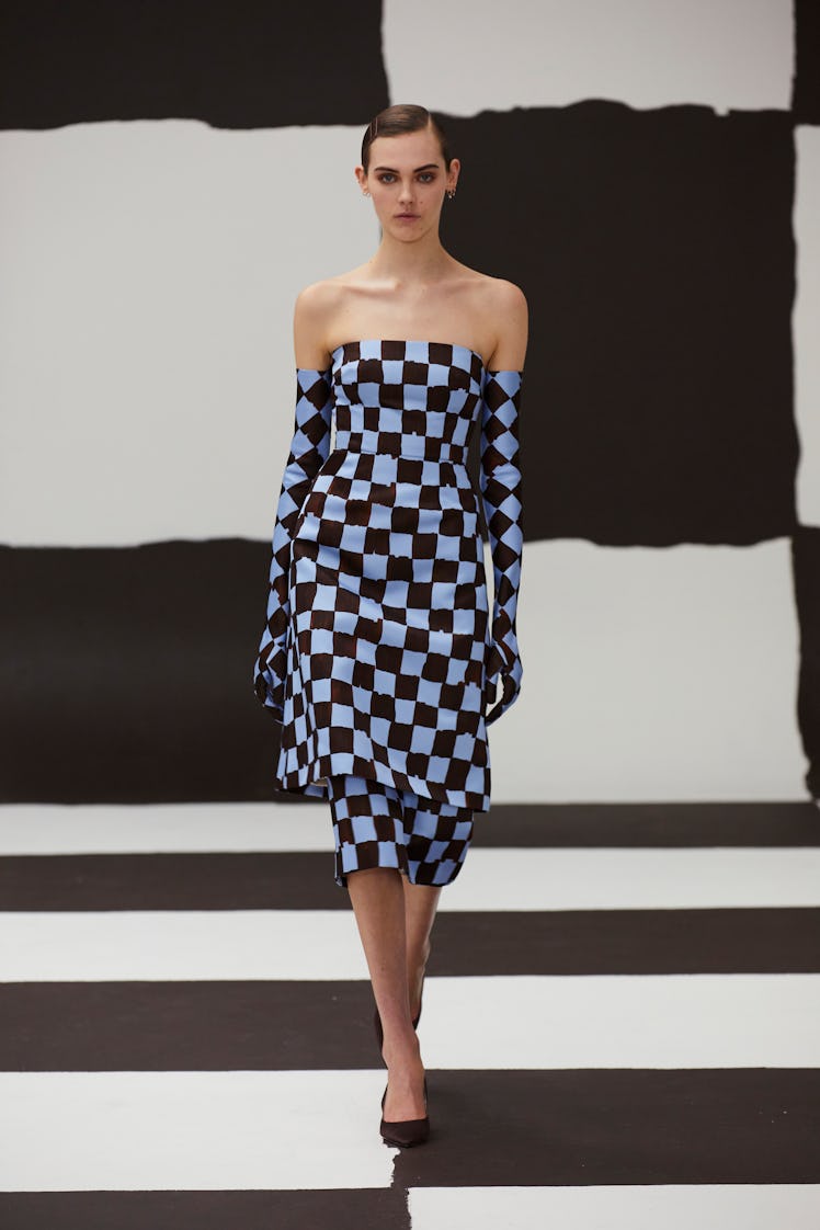 A model in a black-blue checkerboard print dress and gloves by Emilia Wickstead