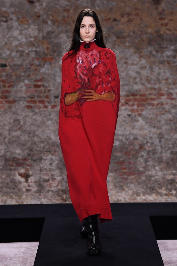 A model wearing a red dress with painted arms by Raf Simons at the London Fashion Week Fall 2022