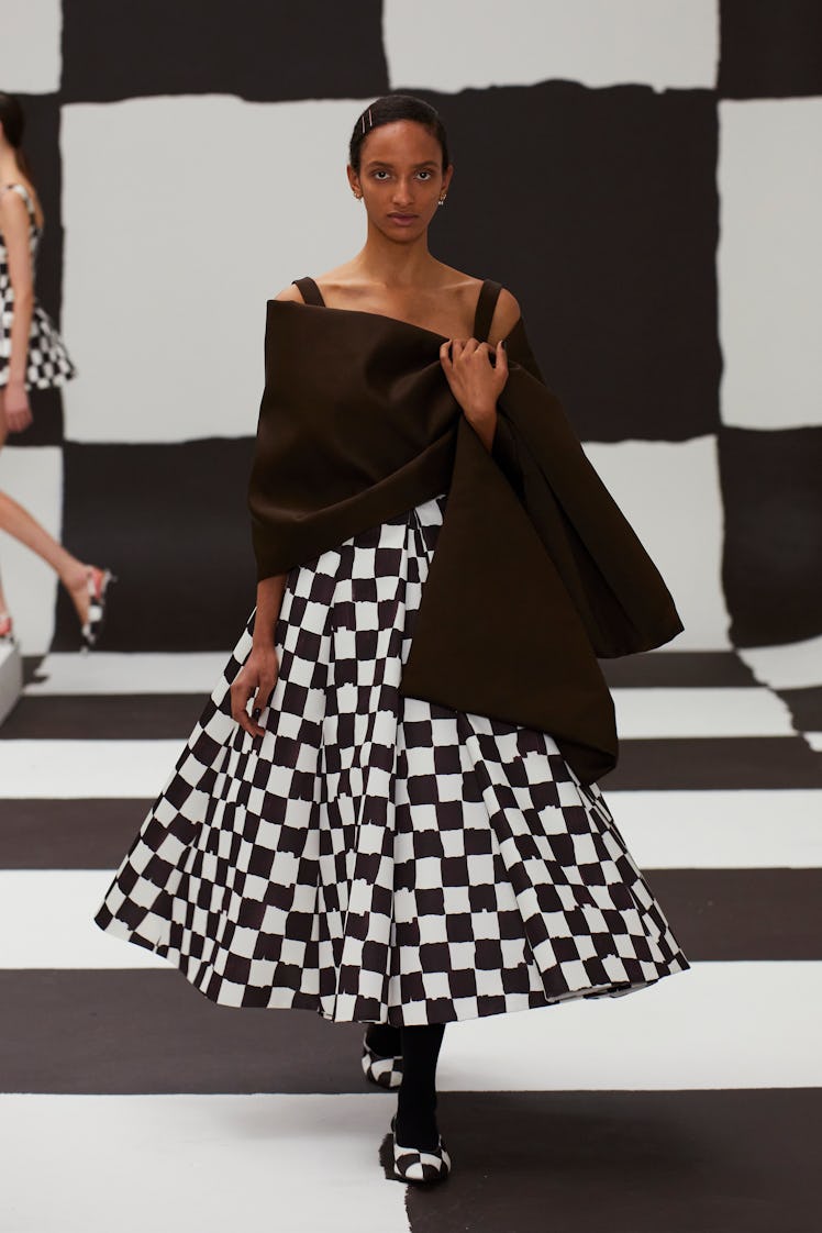 A model in a black-white checkboard print dress and black scarf by Emilia Wickstead