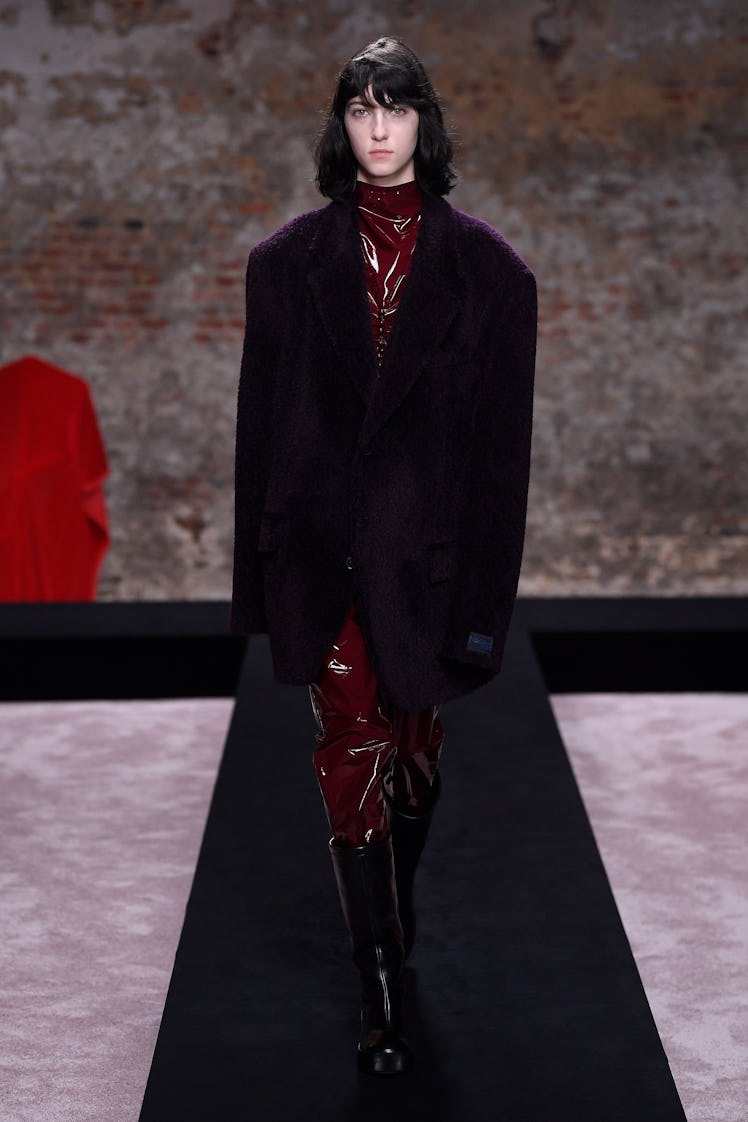 A model wearing a burgundy dress and a black Raf Simons coat at the London Fashion Week Fall 2022