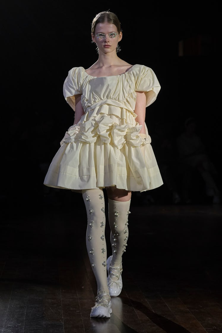 A model in a vanilla puff dress and socks with pearls by Simone Rocha at the London Fashion Week Fal...