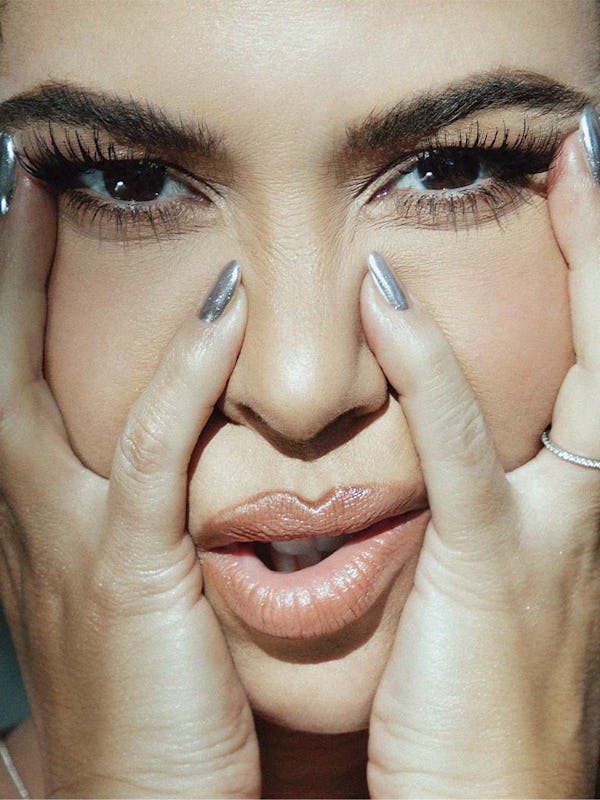 Kourtney Kardashian's zoomed-in face with her hands holding on to her cheeks and touching the sides ...