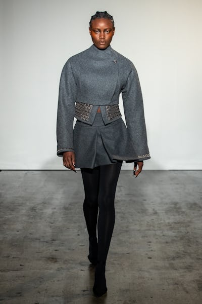 a model wearing a cropped grey miniskirt suit with stud detailing on the Maximilian runway