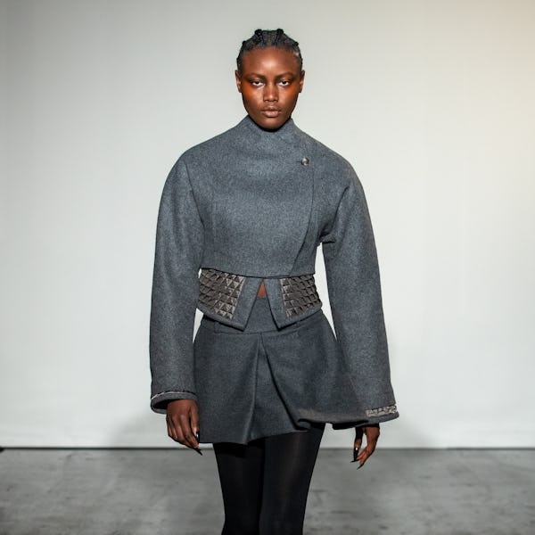 a model wearing a cropped grey miniskirt suit with stud detailing on the Maximilian runway