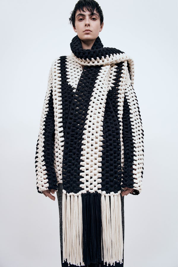 a model wearing a black and white knit cardigan, scarf, and skirt by Partow
