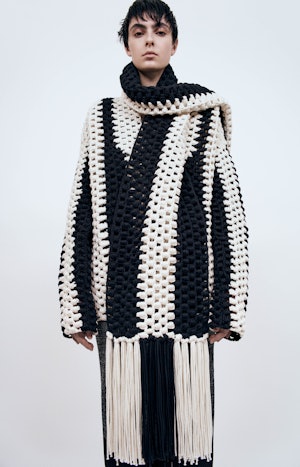 a model wearing a black and white knit cardigan, scarf, and skirt by Partow