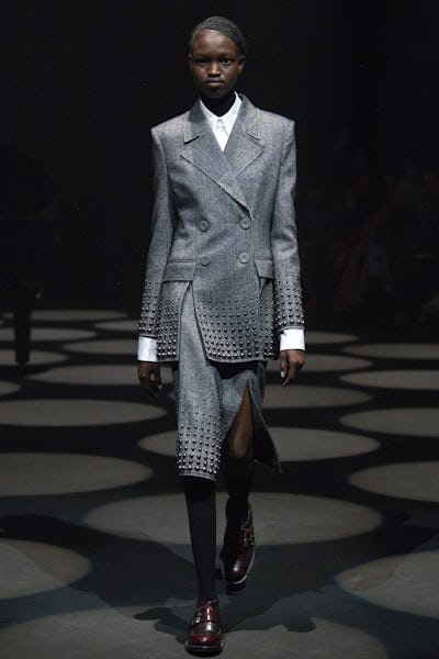 a model wearing a grey blazer and skirt with stud detailing on the Erdem runway