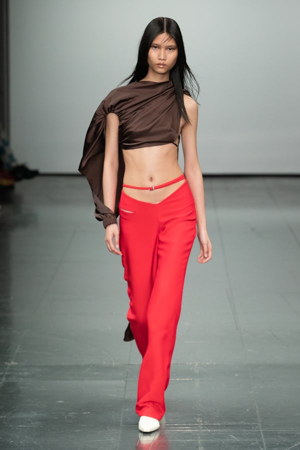 a model wearing a brown silk asymmetric top and low-slung red pants on the Supriya Lele runway