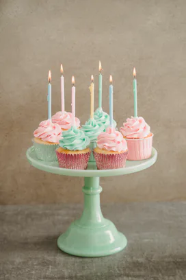 colorful birthday cupcakes on a green milk glass cake stand