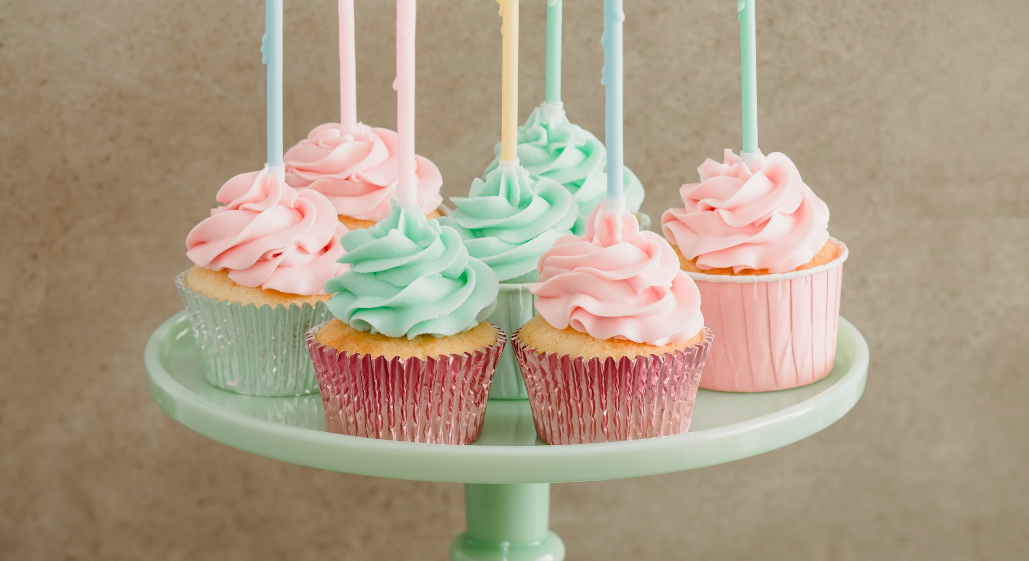 colorful birthday cupcakes on a green milk glass cake stand