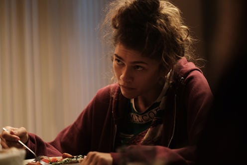 Zendaya as Rue in 'Euphoria.' She's wearing her signature red hoodie and sitting at the kitchen coun...