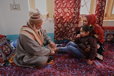 Ali Kaak applying surgical tape on the feet of Sadia, a seven-year-old girl who has recovered fractu...