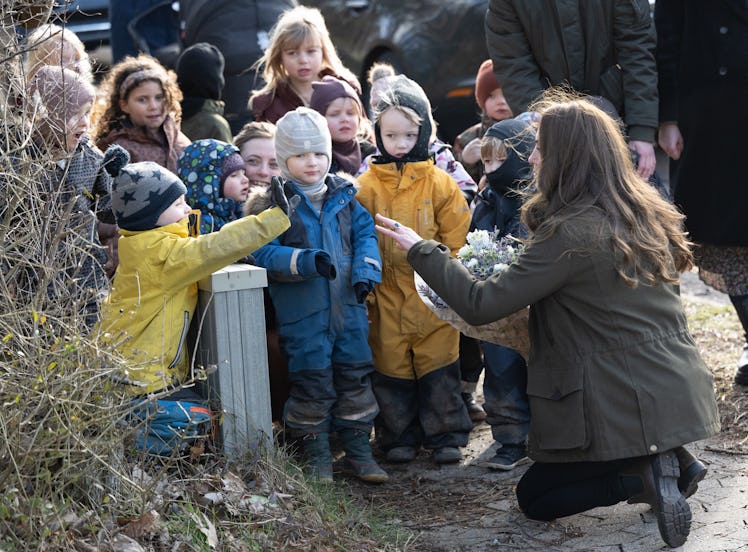 Kate Middleton kneeling down next to a group of children