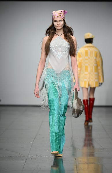 a model wearing a fringe halter top and low-rise turquoise pants on the Conner Ives runway