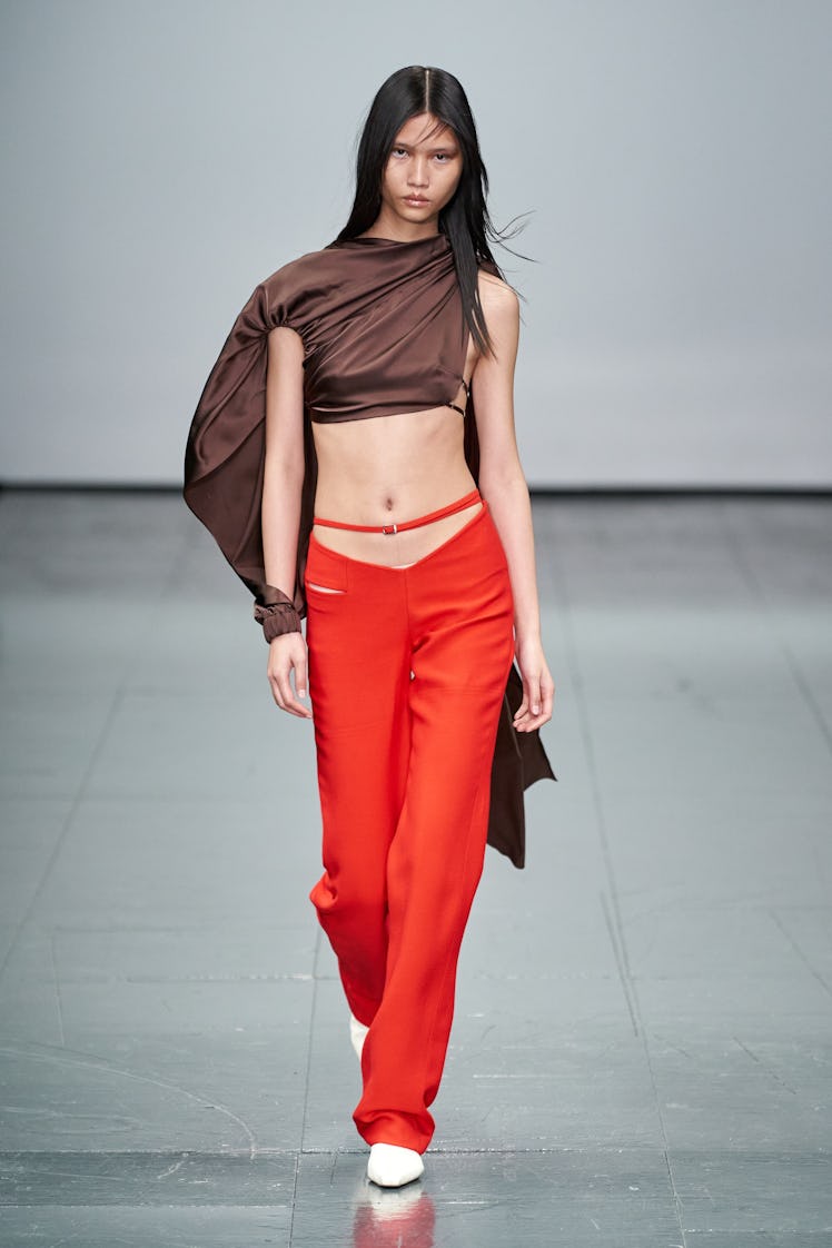 A model wearing a Supriya Lele brown asymmetric top and orange trousers at the London Fashion Week F...