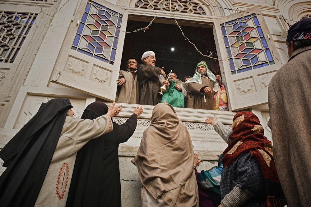  A Kashmiri Sufi preacher distribute sweets and dates to women devotees at a shrine in Khanyar area ...
