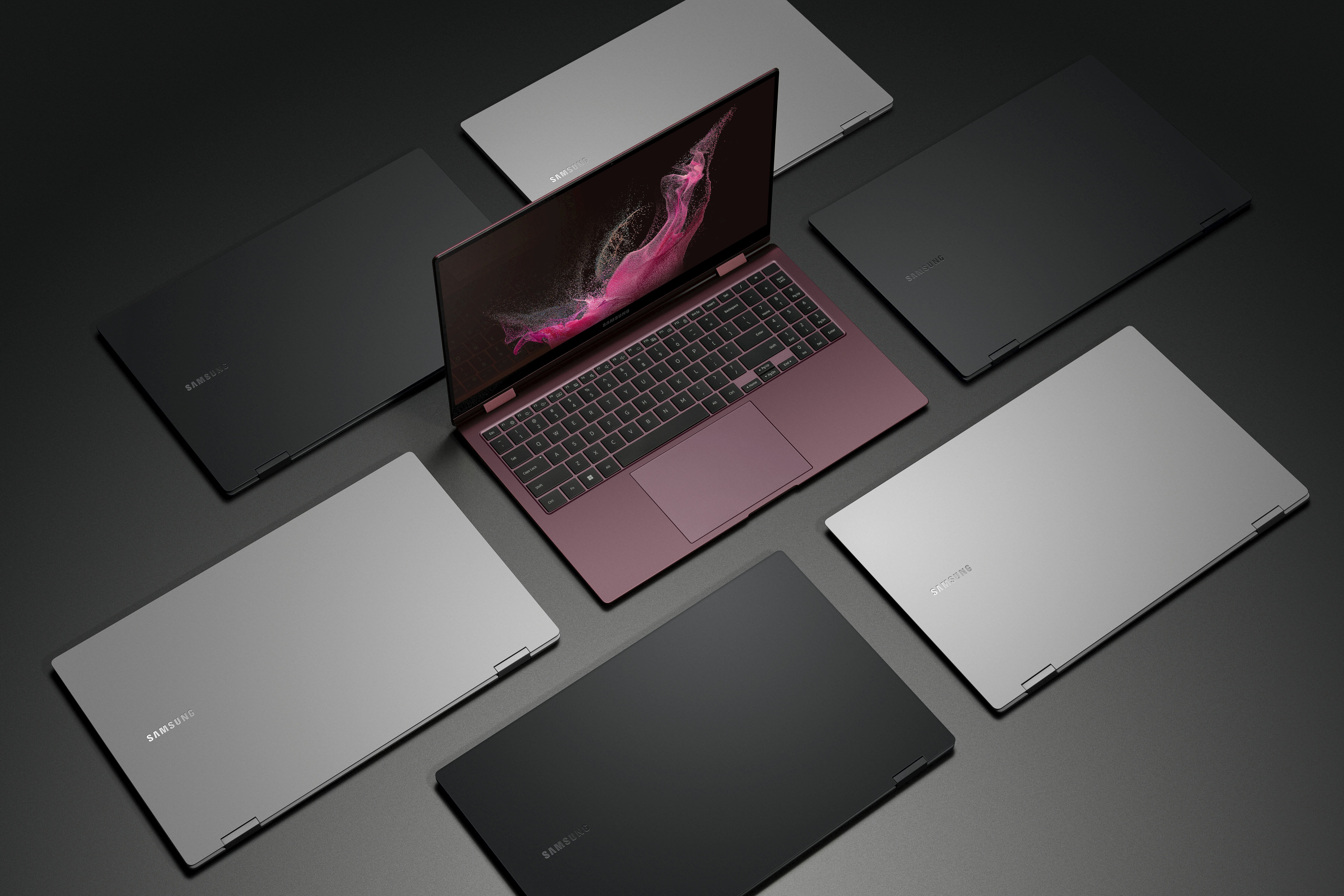 The Galaxy Book 2 Pro 360 in burgundy sitting open surrounded by closed Galaxy Books