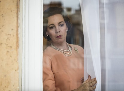 Olivia Colman as Queen Elizabeth II peering out the window