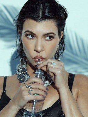 Kourtney drinking water from a bottle with a straw and looking to the side 