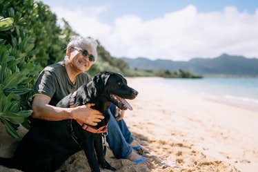 Japanese man sitting with dog on beach