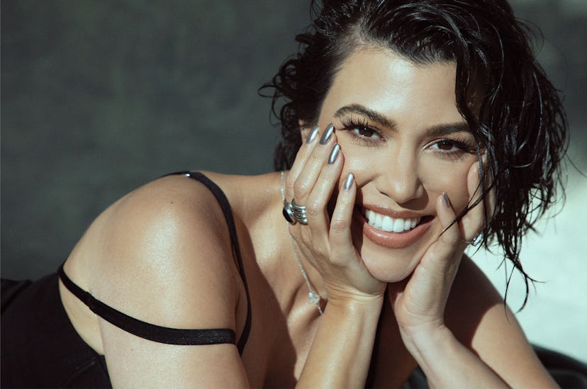 Kourtney Kardashian smiling with her face leaning against her hands
