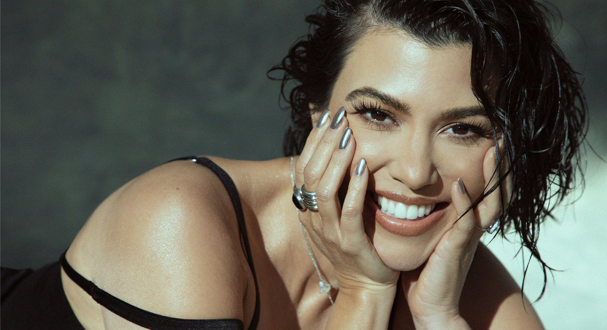 Kourtney Kardashian smiling with her face leaning against her hands
