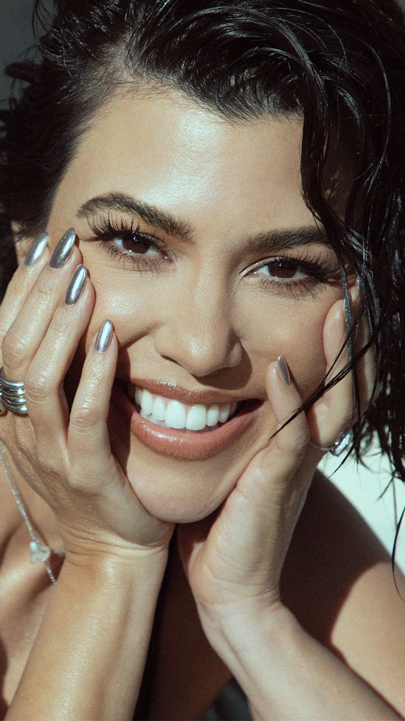 Kourtney Kardashian smiling with her face leaning against her hands
