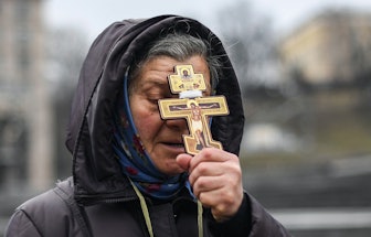 A religious woman holds a cross as she prays on Independence square in Kyiv in the morning of Februa...