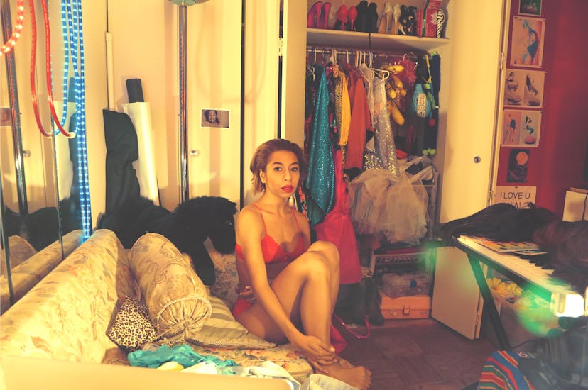 Kia LaBeija sitting on the couch in her room with clothes all over the place