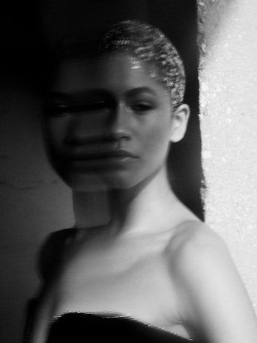 Zendaya with her hair pulled back in a black and white portrait.