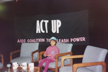A kid sitting in front of an "Act Up" text sign